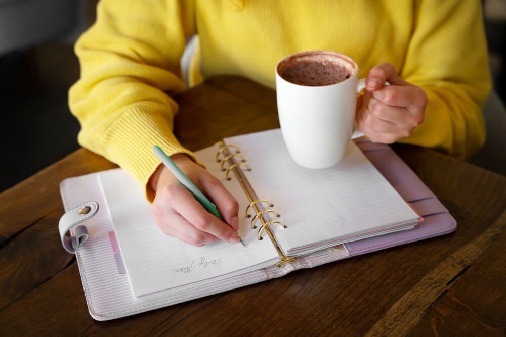 Person Journaling Gratitude In The Morning With A Peaceful Setting Of Coffee And Nature.